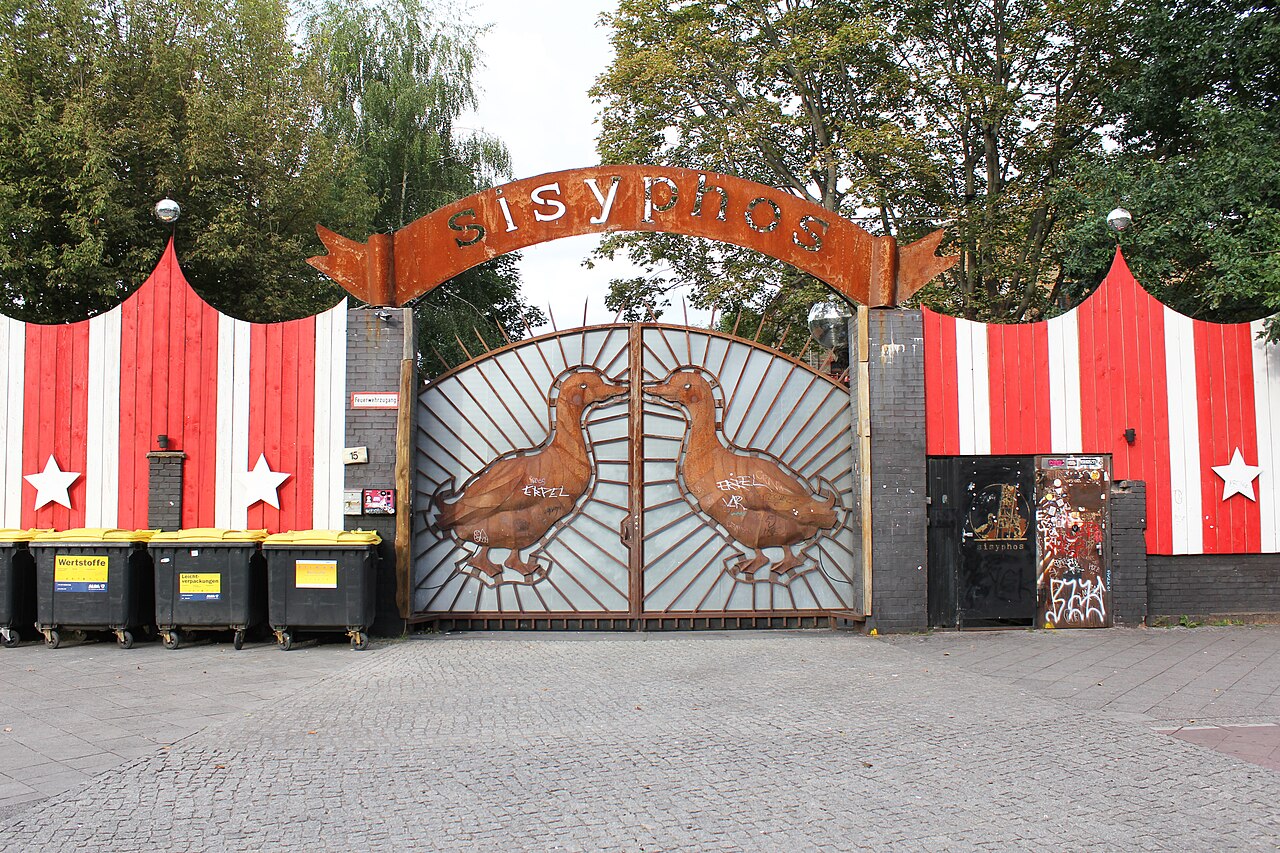Das Eingangstor des Sisyphos mit dem geschmiedeten Schriftzug und zwei Enten