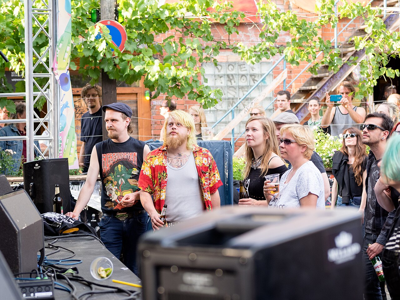 Musiker an einem Mischpult vor Publikum in einem begrünten Hof bei der Fête de la Musique