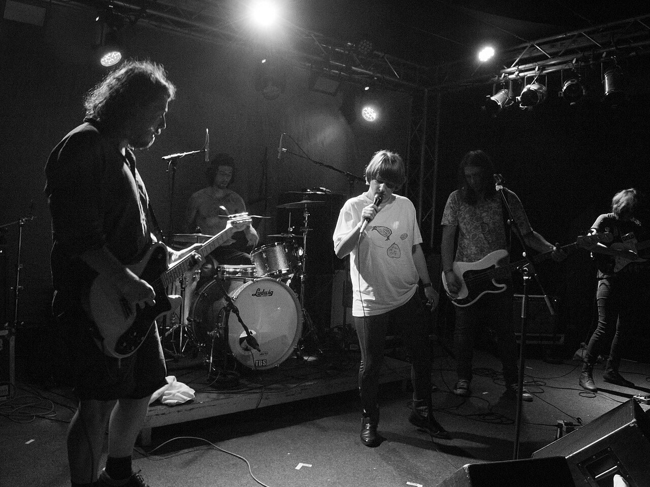 Eine Band auf einer kleinen Clubbühne, in Schwarz-Weiß fotografiert