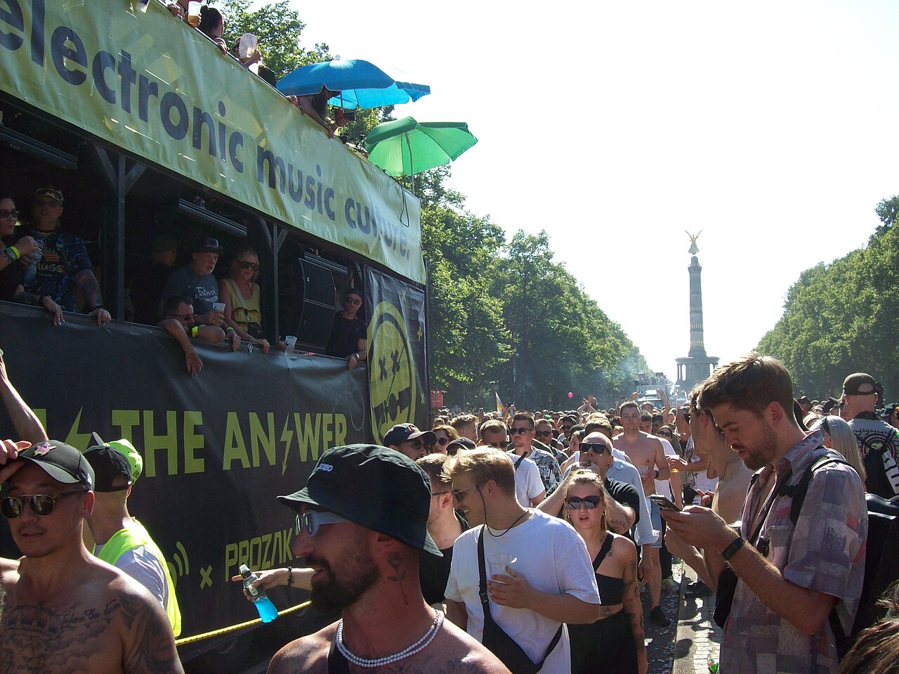 Ein Wagen mit Soundsystem inmitten Tanzender auf der Straße des 17. Juni, im Hintergrund die Siegessäule