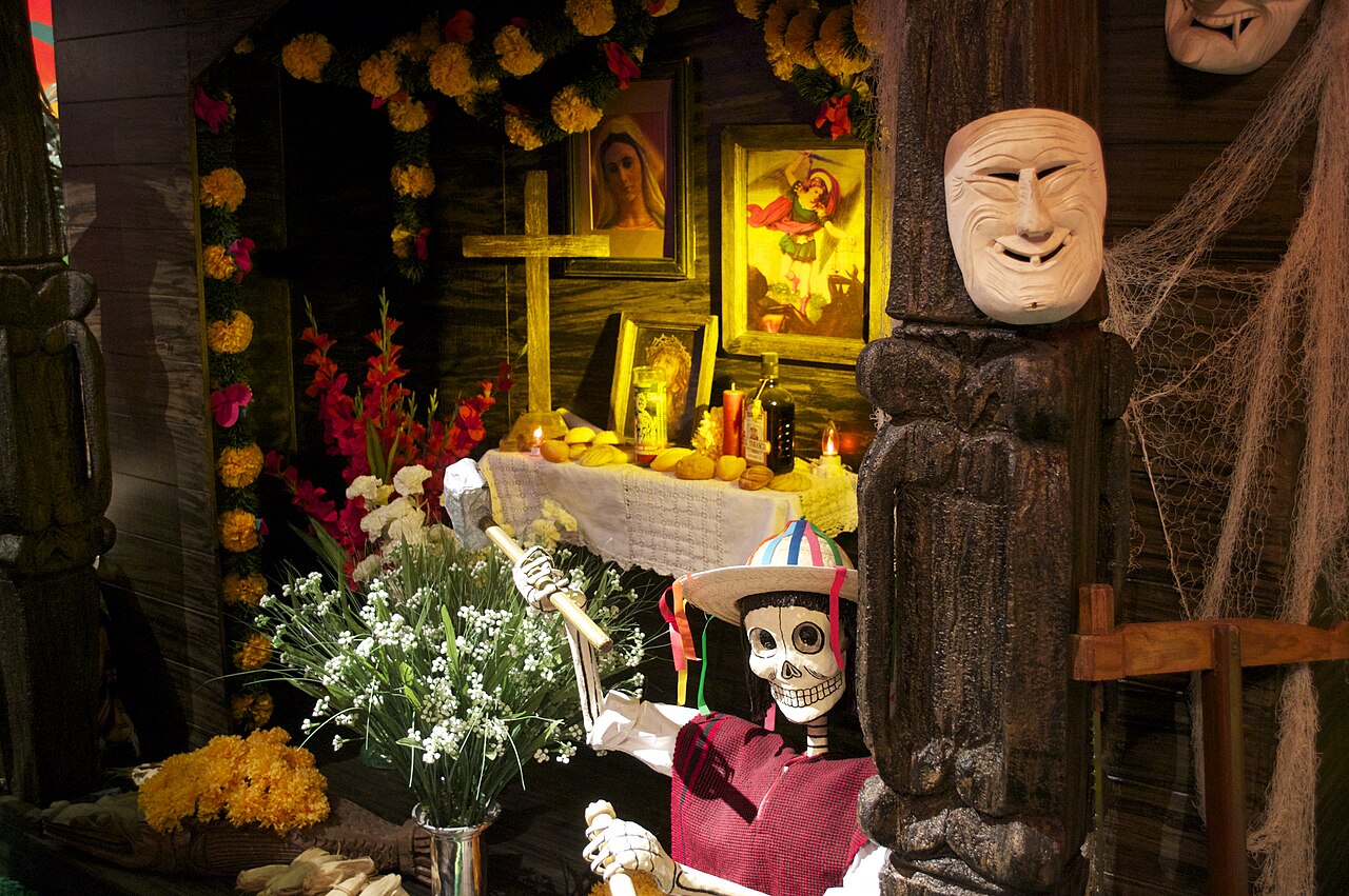 Ein mexikanischer Totenaltar mit Ringelblumen, Heiligenbildern, Kerzen und einer Skelettfigur mit Hut