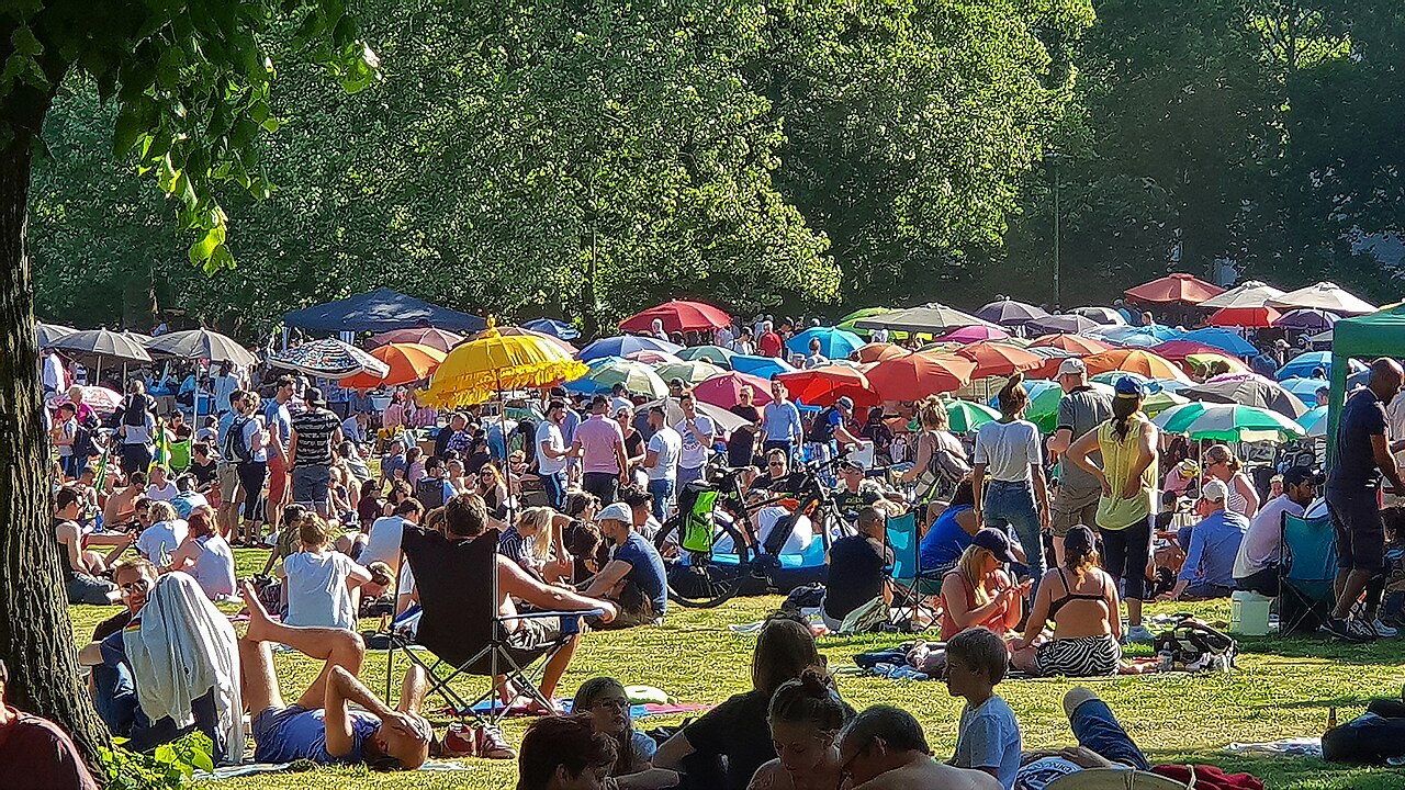 Bunte Sonnenschirme und Picknickdecken dicht an dicht auf der Wiese im Preußenpark