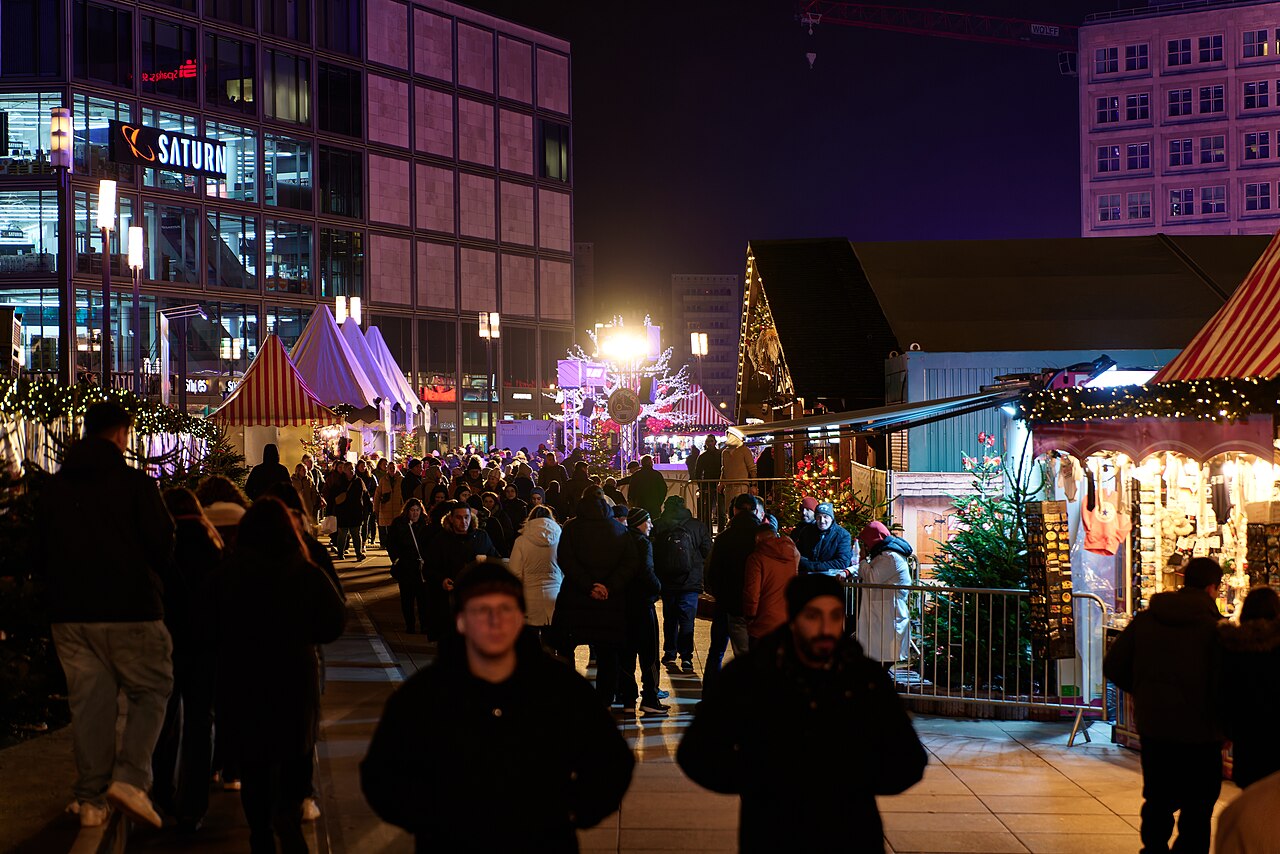 Besucher zwischen beleuchteten Marktbuden auf dem Alexanderplatz bei Nacht