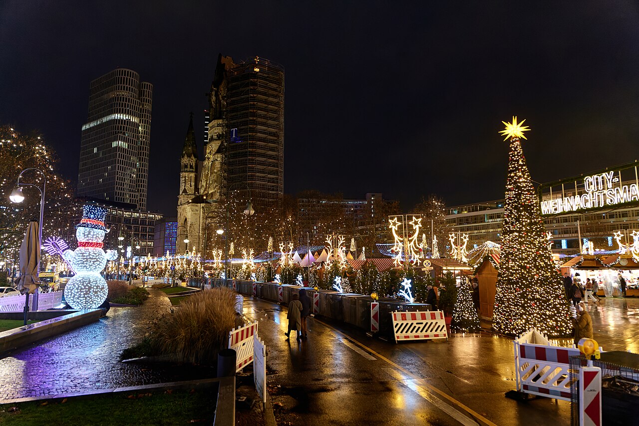 Der Weihnachtsmarkt auf dem Breitscheidplatz bei Nacht mit dem Turm der Gedächtniskirche und einem beleuchteten Weihnachtsbaum