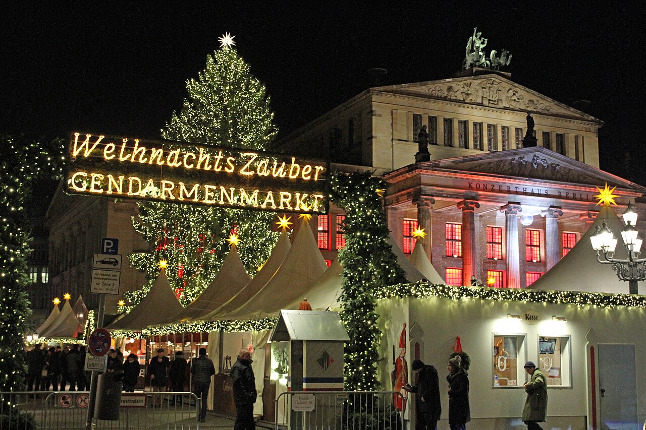 Der beleuchtete Schriftzug WeihnachtsZauber Gendarmenmarkt vor einem Weihnachtsbaum und dem Konzerthaus